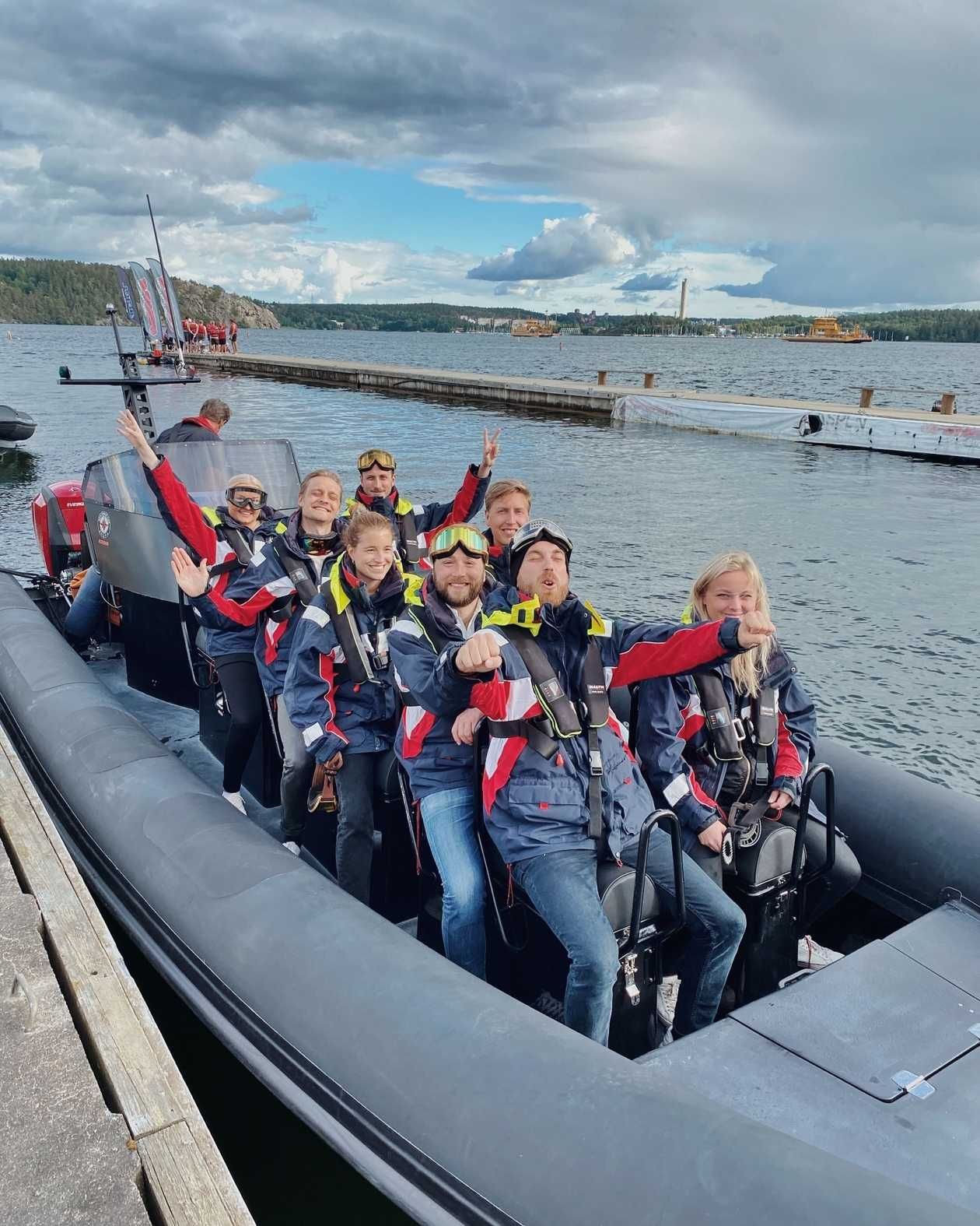 IVEO-kollegor i flytvästar som vinkar från en RIB-båt vid en brygga