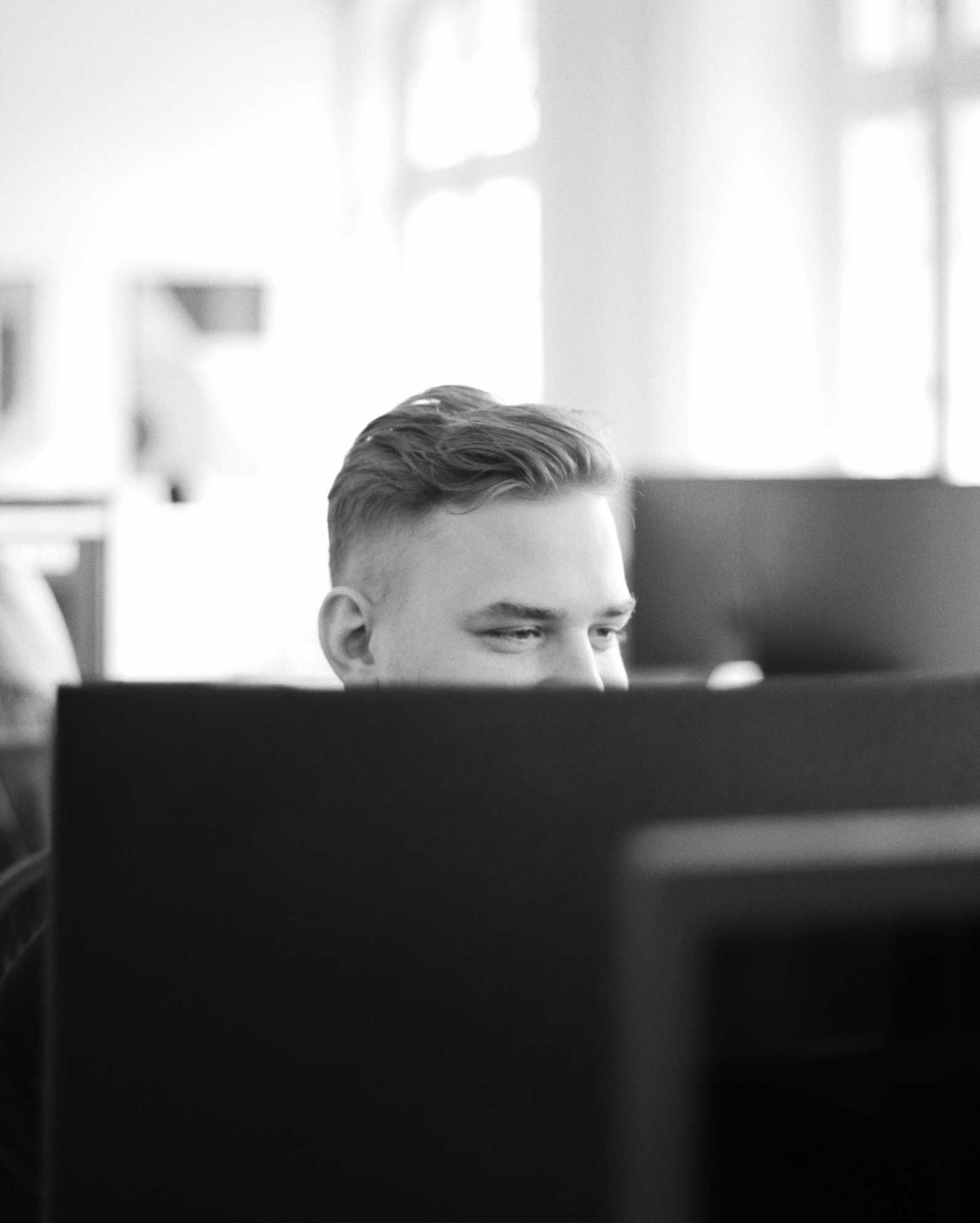 Black and white photo of a colleague behind a computer screen